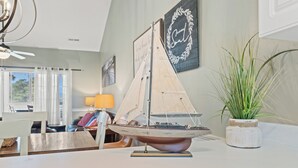 En modelsejlbåd på et bord, en potteplante og en væg med en indrammet citat.