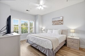 Ein Schlafzimmer mit Bett, Nachttischen, Deckenventilator, Fenster und einem Wandbild.
