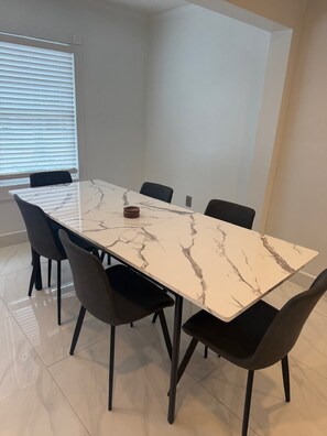 A rectangular dining table with a marble top, surrounded by six black chairs. - The Marble Manor | House & Loft (Myrtle Beach)