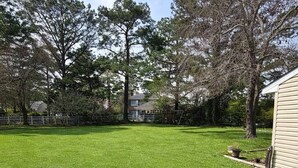 A well-maintained grassy yard with trees and a house in the background. - The Marble Manor | House & Loft (Myrtle Beach)