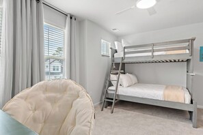 Ein Schlafraum mit Etagenbetten, einer Leiter, einem Stuhl und einem Deckenventilator.