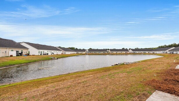 Un quartier résidentiel avec des maisons, un étang et une zone herbeuse.