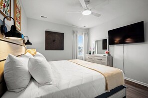 A bedroom with a bed, a ceiling fan, a TV, a dresser, and a window with curtains. - Mermaid Soirée near the Beach (Myrtle Beach)