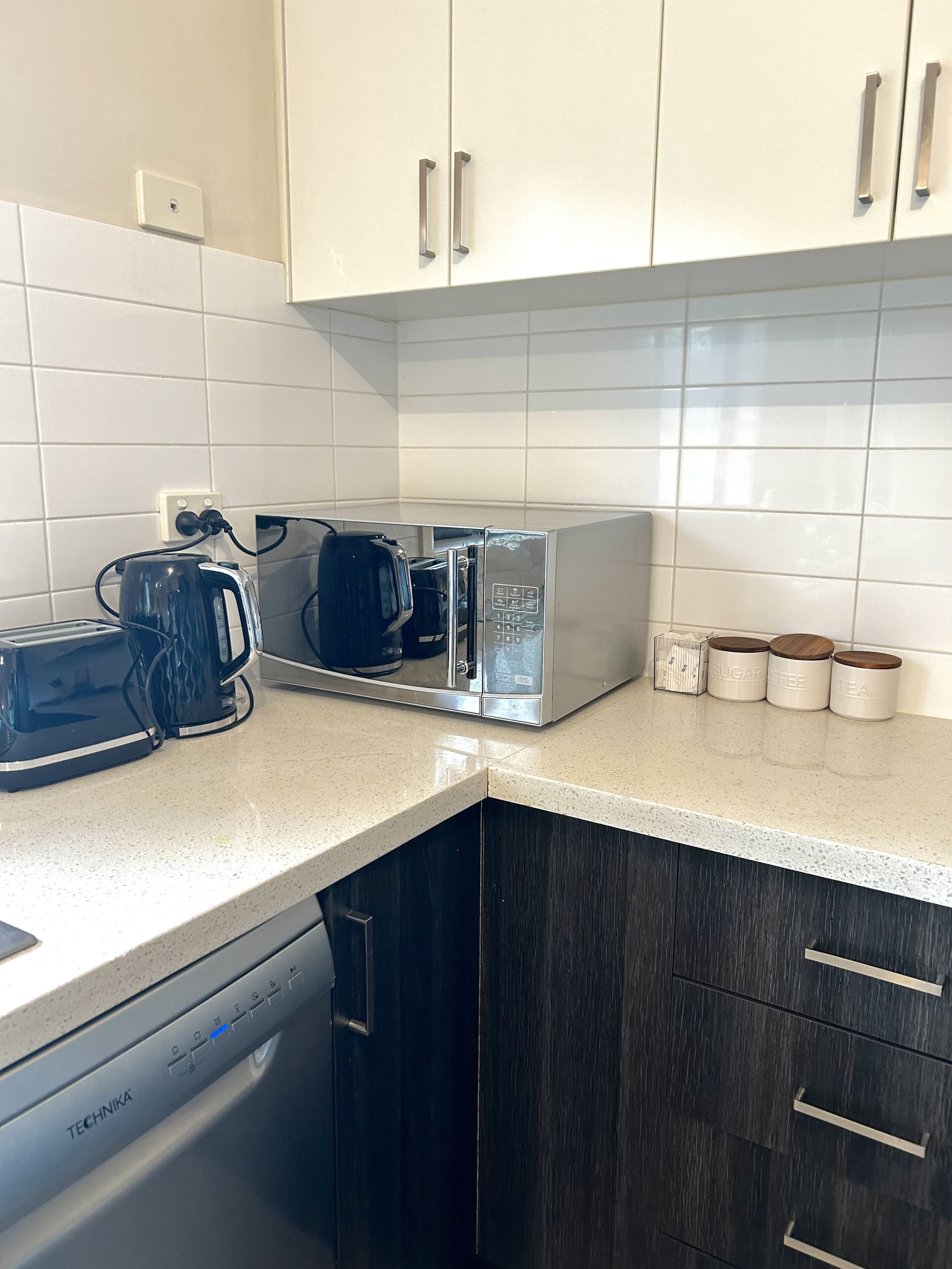 A kitchen with white cabinets, a microwave, a toaster, and a coffee maker.