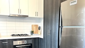 Een moderne keuken met witte kastjes, een roestvrijstalen koelkast, een ingebouwde oven en een gasfornuis.