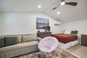 Ein Schlafzimmer mit Bett, Sofa, Sessel, Deckenventilator und einem Bild an der Wand.