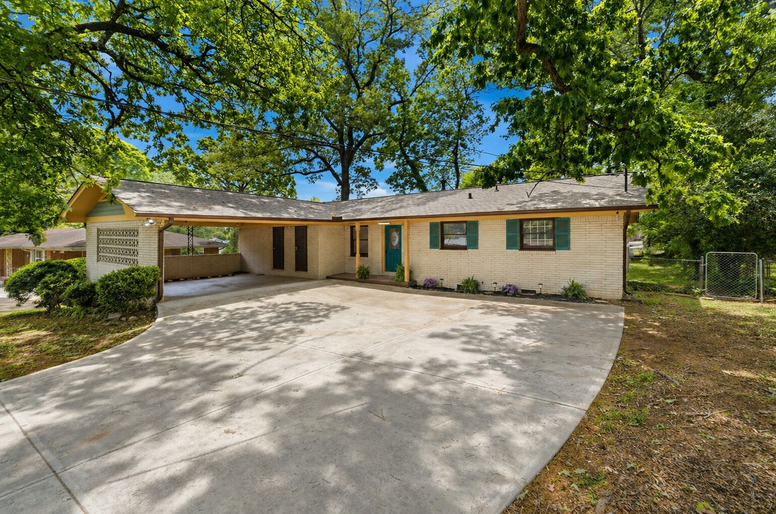 A single-story building with a covered porch, a brick exterior, and a front yard with trees.