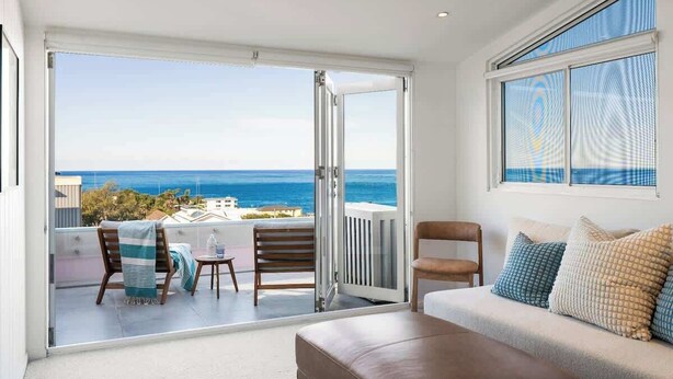 Een balkon met uitzicht op de oceaan, een bank en een stoel.