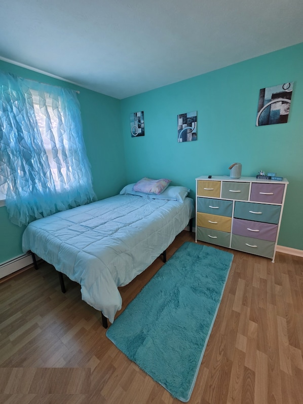 A bedroom with a bed, a dresser, a rug, and wall art.