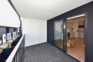 Ein modernes Apartment mit Balkon, einer Schiebetür zum Küchenbereich und Blick auf die Nachbargebäude.