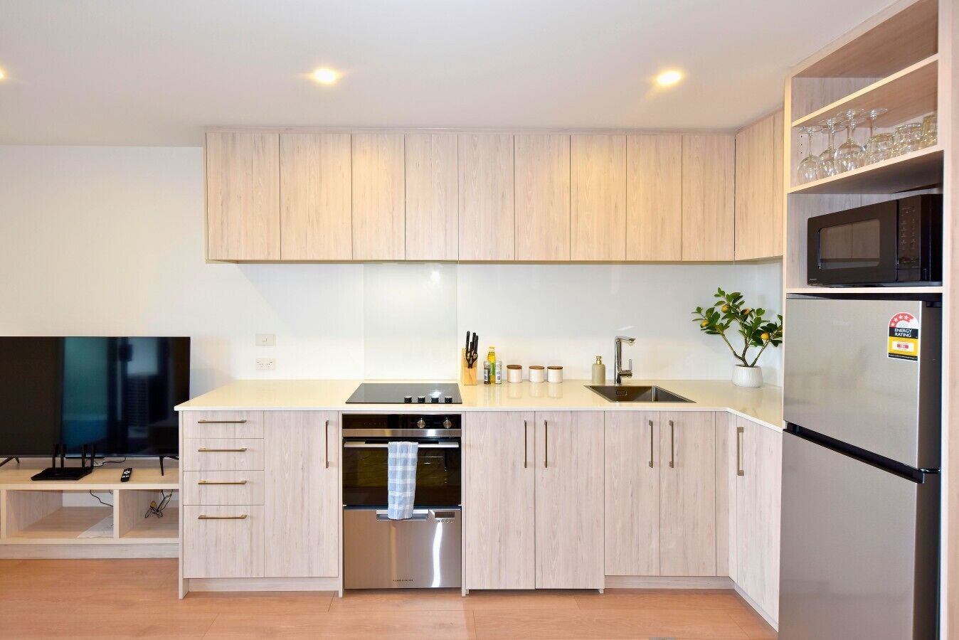 A modern kitchen with wooden cabinets, stainless steel appliances, a built-in oven, and a microwave.