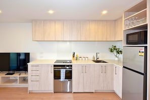 Eine moderne Küche mit Holzausstattung, Edelstahlgeräten, einem Backofen und einer Mikrowelle.