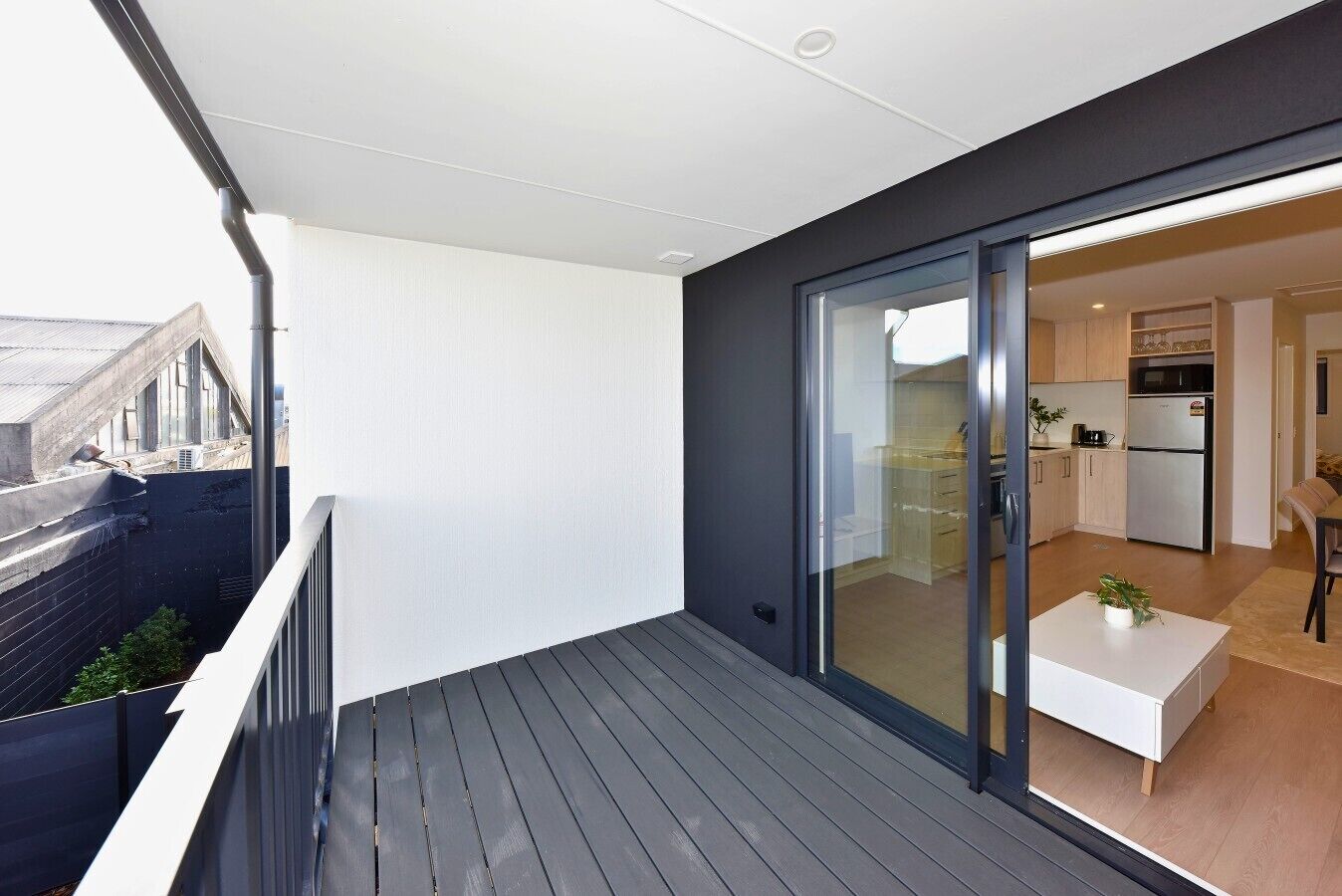 Eine moderne Wohnung mit einem Balkon, einer Schiebetür zu einer Küche und Blick auf die Stadt.