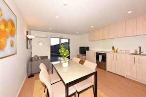 Eine moderne Wohnung mit Essbereich, Küchenzeile und einem Balkon mit Pflanze.