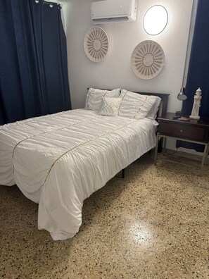 A bedroom with a bed, a nightstand, a lamp, a decorative lighthouse, and a wall-mounted air conditioner. - Family house with Sea View (arroyo)