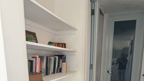 A hallway with a white door, a white wall, and a speckled floor.