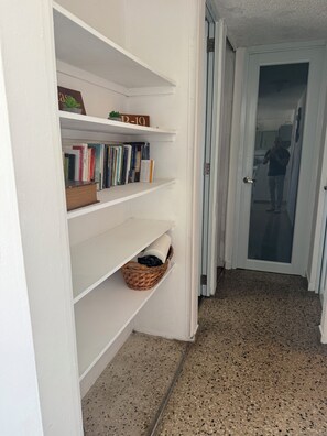 Un pasillo con una puerta blanca, una pared blanca y un piso moteado.