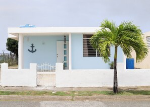 A modern house with a white exterior, a blue door, and a palm tree in the front yard. - Family house with Sea View (arroyo)