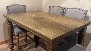 A rectangular wooden table with four upholstered chairs, each with a buttoned backrest. - Cottage No. 4 on Ranch with Fishing & Camping (McKinney)