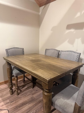 A rectangular wooden table with four upholstered chairs, each with a buttoned backrest.