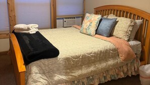 A bedroom with a wooden bed, a ceiling fan, and a window with blinds. - Cottage No. 4 on Ranch with Fishing & Camping (McKinney)