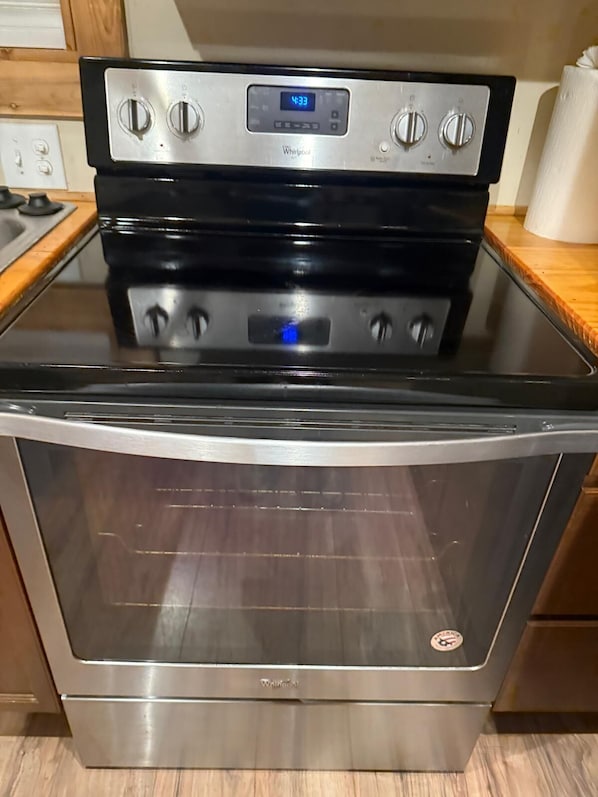 A stainless steel Whirlpool oven with a digital clock, control knobs, and a glass top.