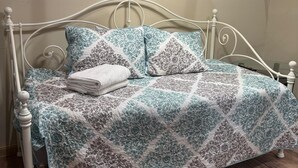 A bed with a patterned bedspread, pillows, and a folded blanket. - Cottage No. 4 on Ranch with Fishing & Camping (McKinney)