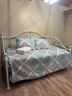 A bed with a patterned bedspread, pillows, and a folded blanket.