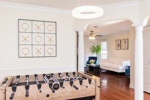 Ein Zimmer mit einem Kicker, einem gerahmten abstrakten Kunstwerk und einer Kristallleuchter.