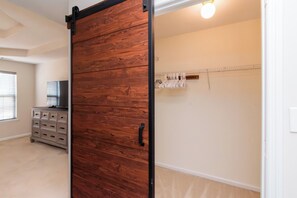 Ein Zimmer mit einer schiebbaren Holztür, einem Schminktisch, einem Kleiderständer und einem Fernseher.