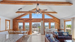 Un interior espacioso con techo alto, vigas de madera, zona de comedor y área de estar con vistas a la playa.