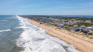 Un pueblo costero con propiedades frente a la playa, una playa de arena y vista al océano.