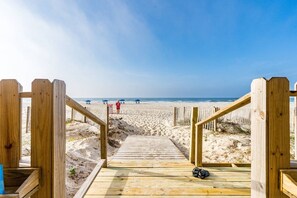 A wooden boardwalk leading to a sandy beach with a clear sky. - Crystal Shores 1307 | Pools + Hot Tub (Gulf Shores)
