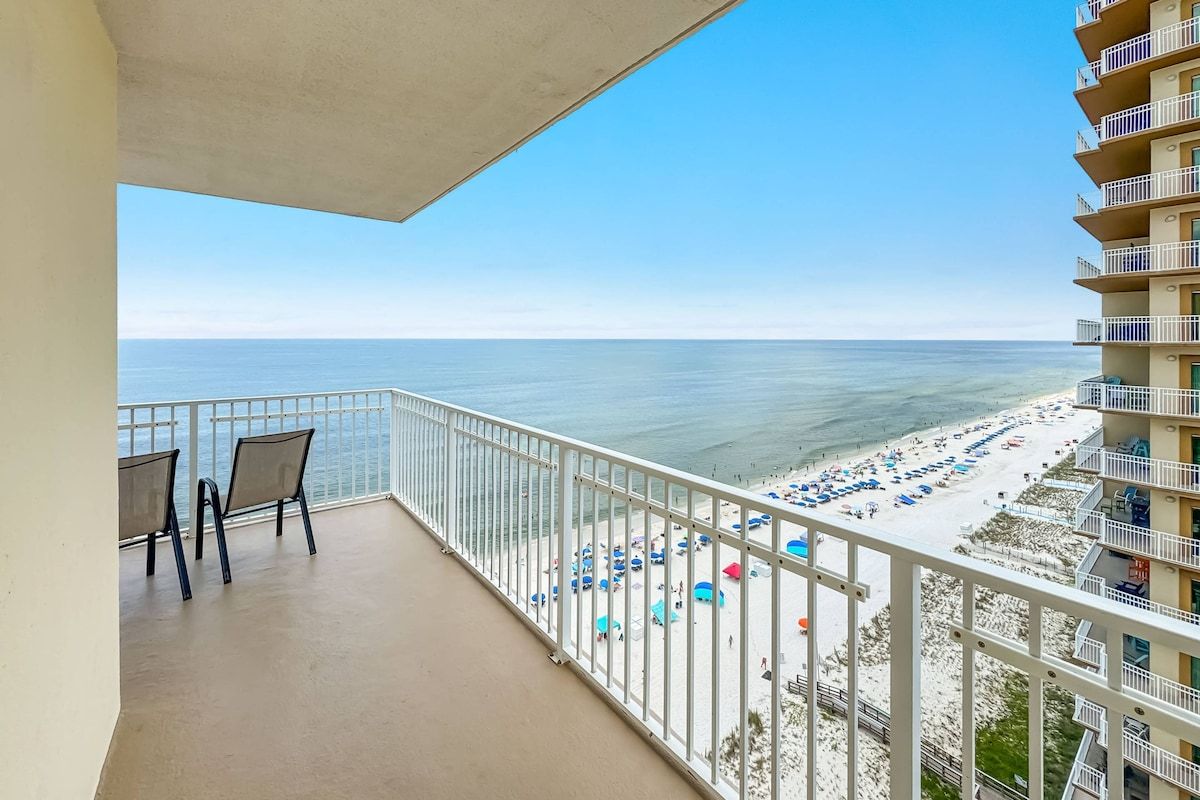 Un balcon donnant sur une plage, avec des chaises et une balustrade.
