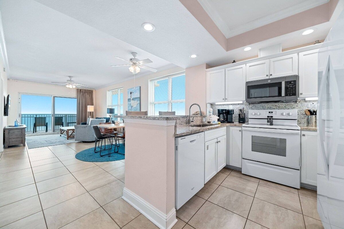 A modern kitchen with white cabinetry, a granite countertop, and a built-in microwave.