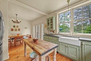 Una cocina con suelo de madera, una mesa de comedor y armarios verdes.