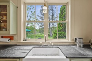 Una cocina con un ventanal amplio, un lavabo y una cafetera.