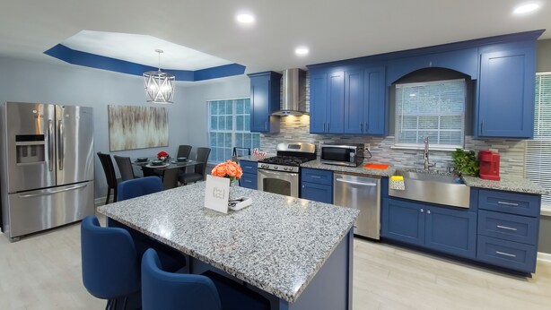 A modern kitchen with blue cabinets, stainless steel appliances, and a granite island. - Beautiful 3-bedroom Serenity house in a Cul-de-Sac with AC in charming Decatur (Decatur)