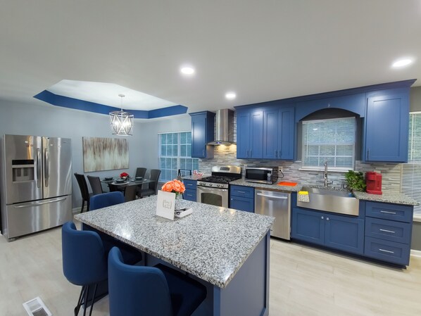 A modern kitchen with blue cabinets, stainless steel appliances, and a granite island. - Beautiful 3-bedroom Serenity house in a Cul-de-Sac with AC in charming Decatur (Decatur)