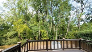 A wooden deck with a railing, surrounded by trees and a pond. - Beautiful 3-bedroom Serenity house in a Cul-de-Sac with AC in charming Decatur (Decatur)