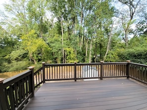 A wooden deck with a railing, surrounded by trees and a pond. - Beautiful 3-bedroom Serenity house in a Cul-de-Sac with AC in charming Decatur (Decatur)