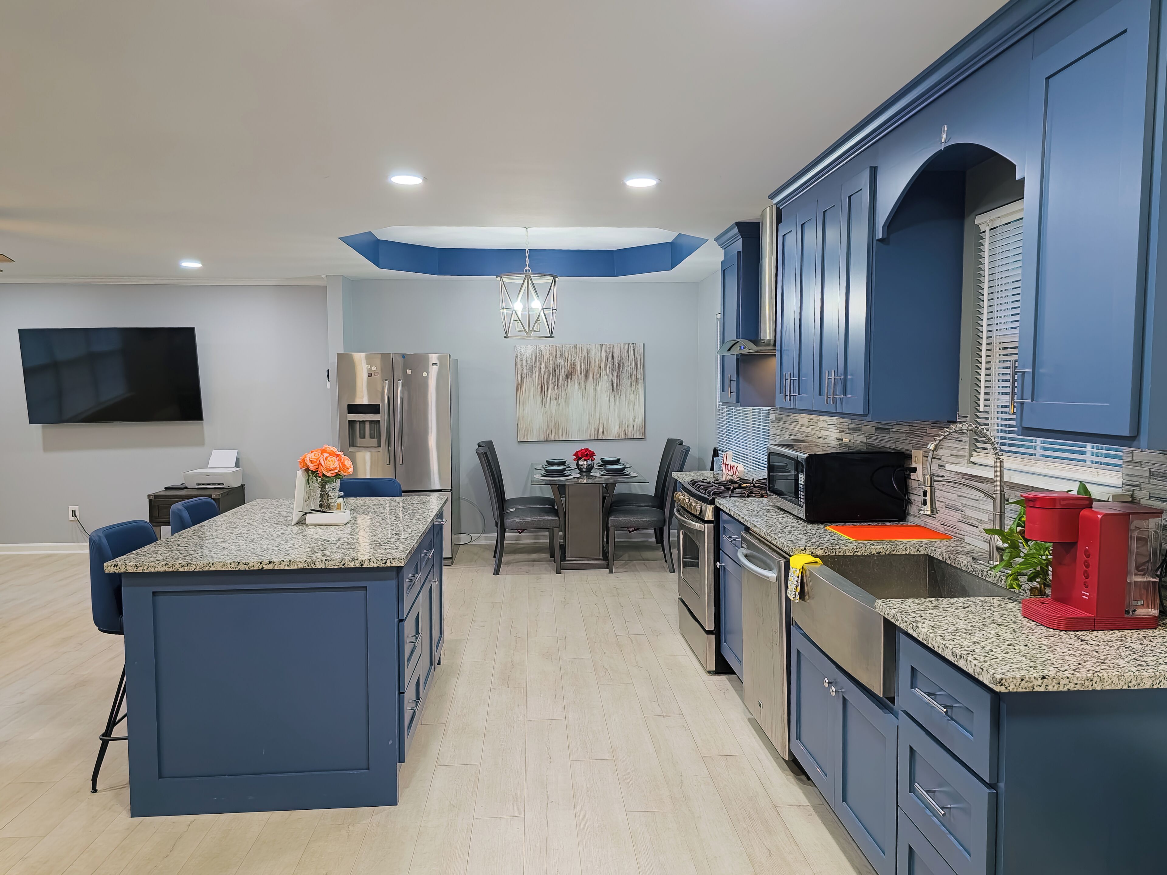 A modern kitchen with blue cabinets, a granite countertop, and stainless steel appliances.