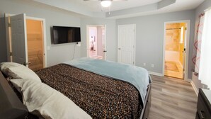 A bedroom with a bed, a ceiling fan, a TV, and a door leading to another room. - Beautiful 3-bedroom Serenity house in a Cul-de-Sac with AC in charming Decatur (Decatur)