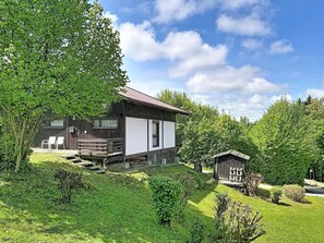 A rustic cabin with a wooden exterior, a balcony, and a small shed in a lush green setting. - Ferienpark Vorauf by Interhome (Siegsdorf)