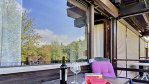 Een terras met een tafel, een fles wijn, een glas en stukken watermeloen.