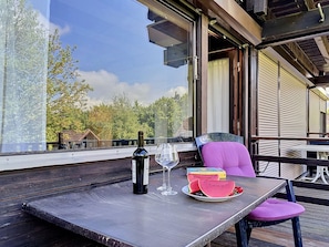 An outdoor seating area with a table, a bottle of wine, a glass, and watermelon slices. - Ferienpark Vorauf by Interhome (Siegsdorf)