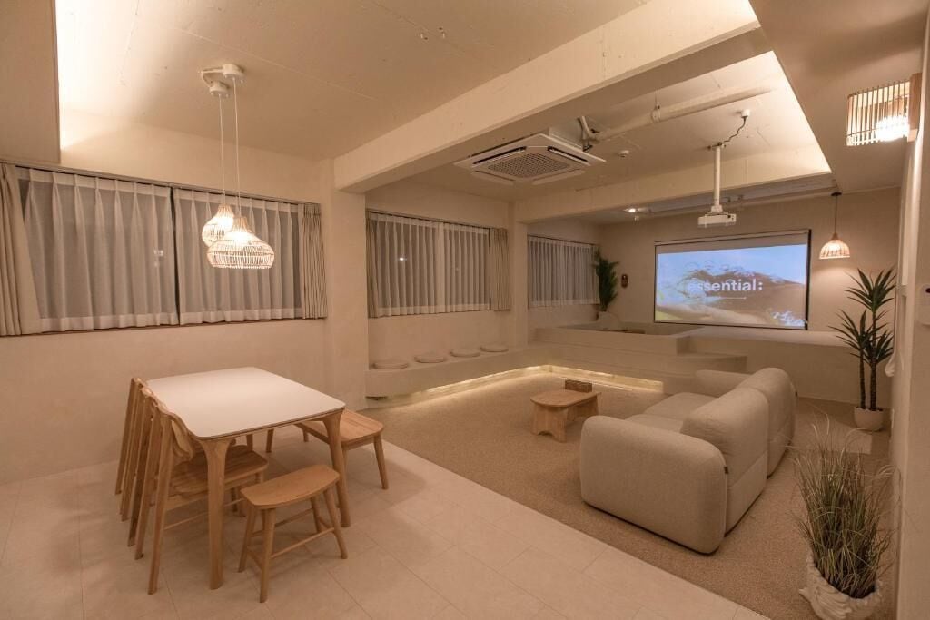 Un salon moderne avec un canapé blanc, une table à manger et des chaises, un grand écran et un projecteur au plafond.