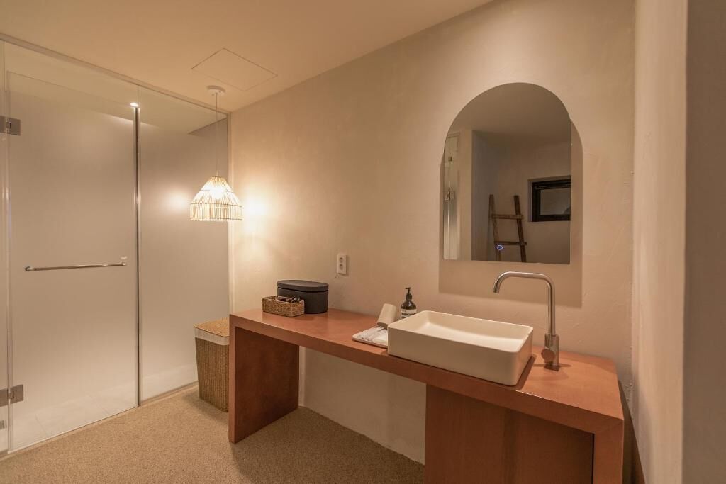 A modern bathroom with a large mirror, a sink, and a shower area.