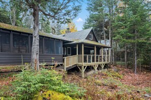 Una baita con veranda in legno, immersa in una fitta foresta.