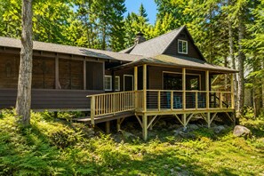 Une cabane dotée d’une terrasse, entourée d’une forêt dense.